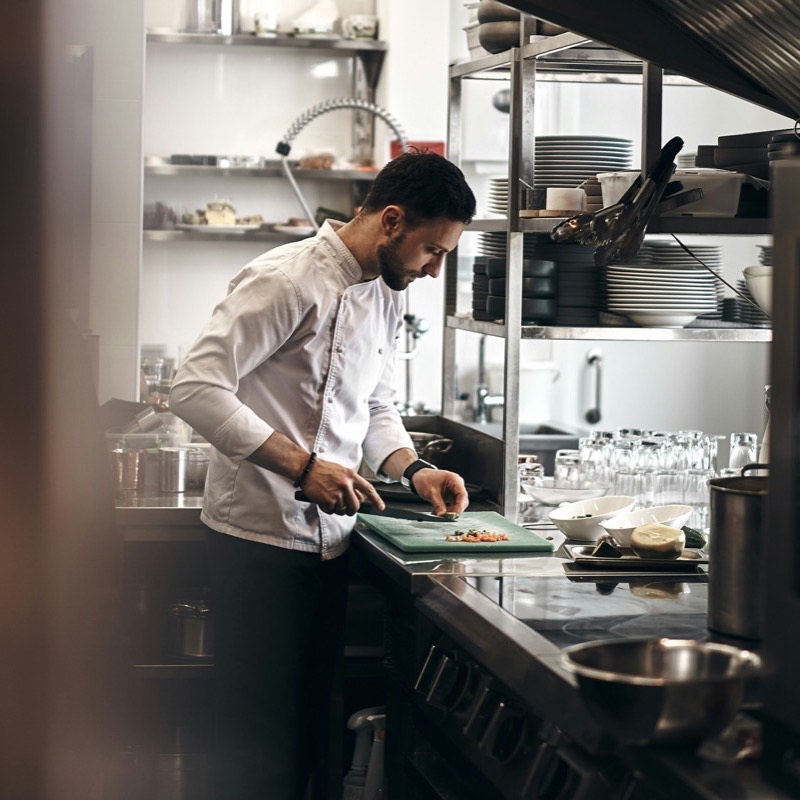 Koch schneidet Gemüse in der Restaurantküche
